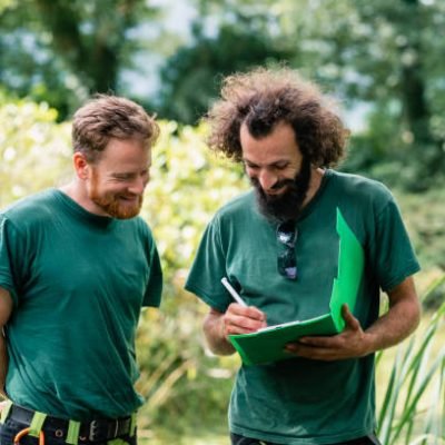 Two men planning ground works on estate, writing ideas and smiling